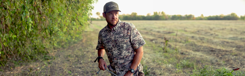 Man holding a rope outdoors wearing GameGuard Digital Camo Explorer Shirt and Juniper Cap