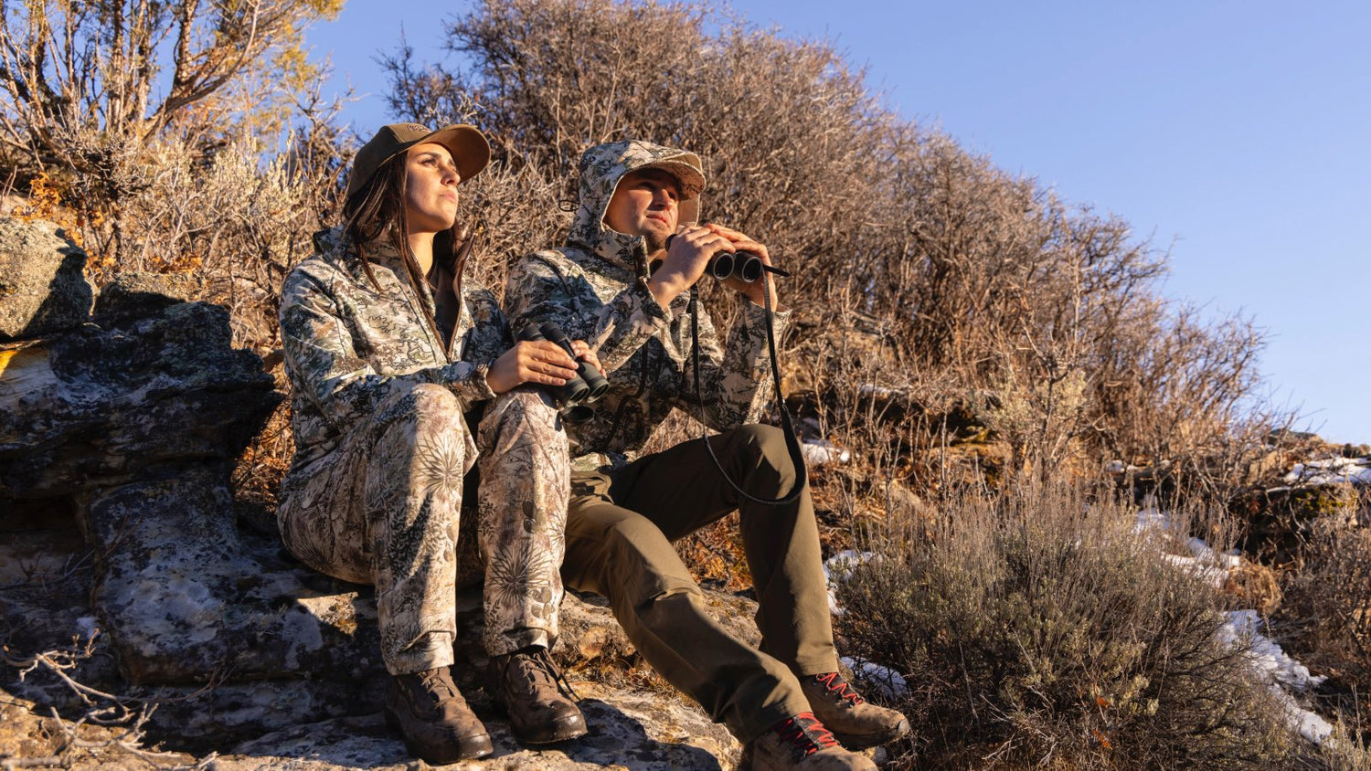 Man and woman outdoors in the mountains wearing GameGuard Camo and Digital Camo in GameGuard Guia Grande jackets and pants.