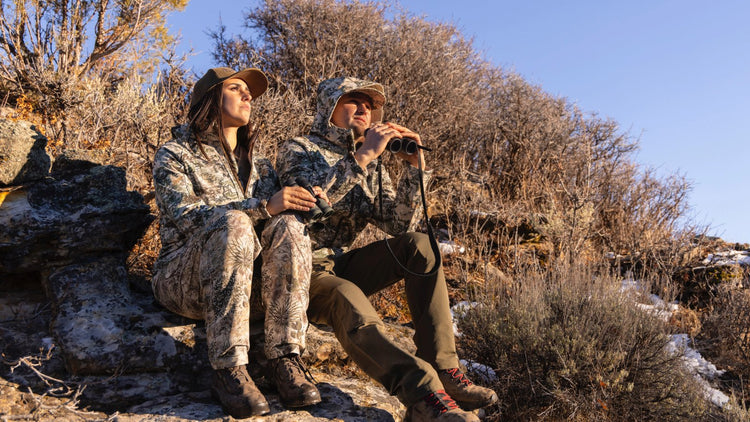 Man and woman outdoors in the mountains wearing GameGuard Camo and Digital Camo in GameGuard Guia Grande jackets and pants.