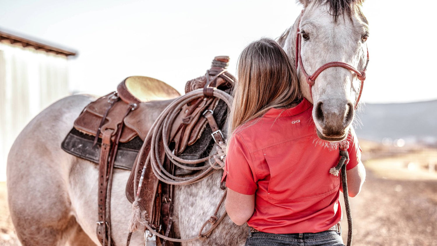 LADIES'. Woman in GameGuard Ladies’ Original Shirt stands with saddled horse. Outdoor women’s shirt, flattering fit, UPF 50+, vented, quick-dry, stain-resistant, lightweight shirt, performance wear, GameGuard gear for women, active outdoor apparel.