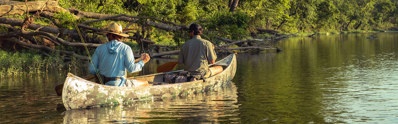 Two men outdoors fishing sitting on boat wearing GameGuard Defender Hoody and MicroTek Shirt