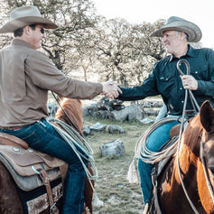 FARM. Cowboys shake hands on horseback wearing GameGuard Original and Drover Shirts. Ranch-ready shirts, UPF 50+, western workwear, durable rodeo gear, moisture-wicking outdoor shirts, mechanical stretch, GameGuard ranch apparel, classic fit farm shirts.