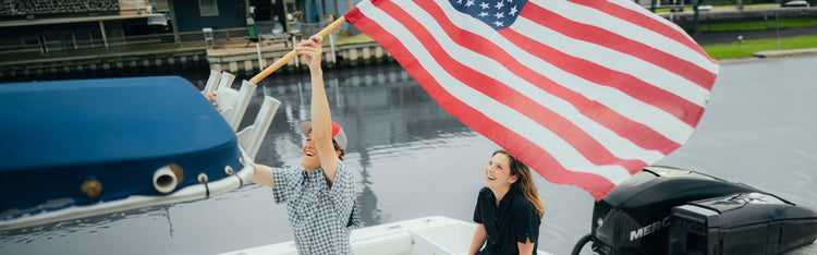 two people raising american flag while wearing GameGuard Shirts and cap for men and women