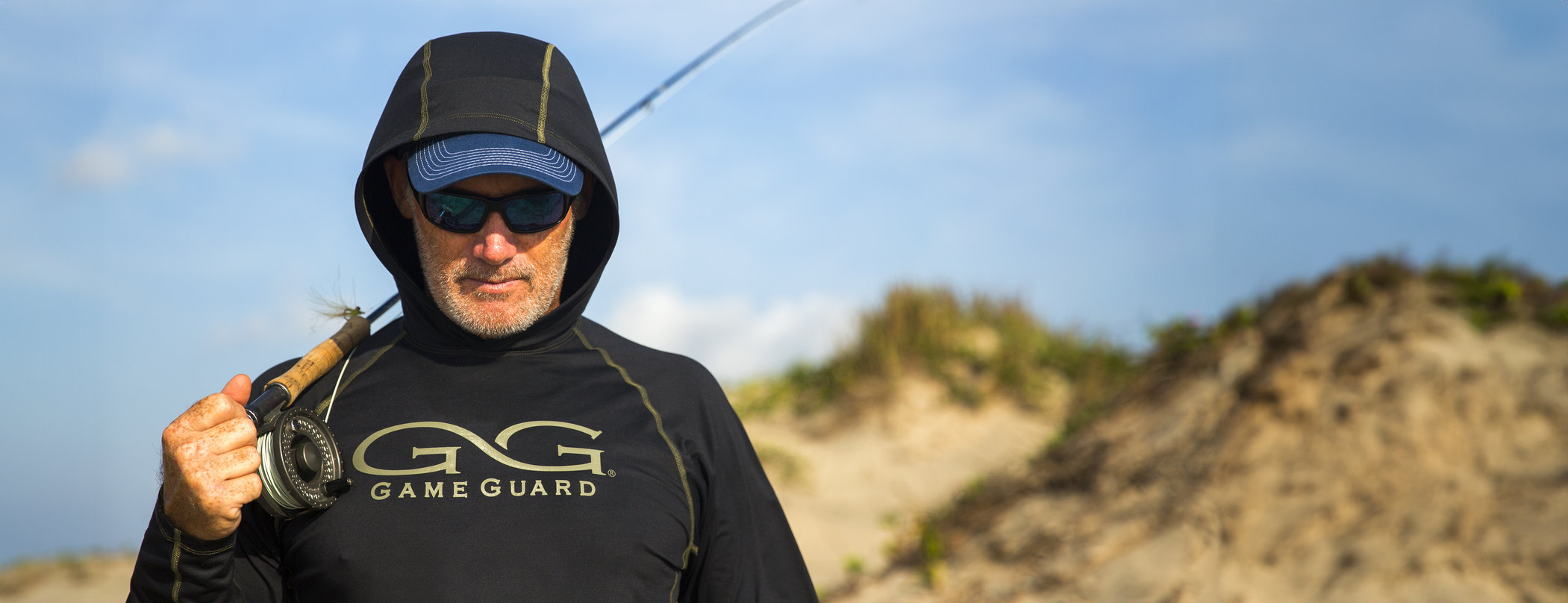 man carrying fishing pole wearing gameguard caviar performance hoody