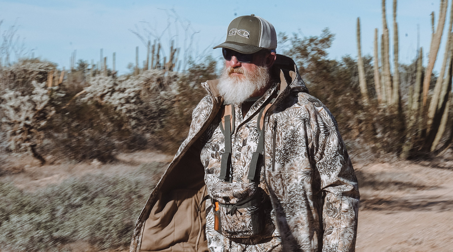 man wearing gameguard guia grande jacket and vest, bino case, and gameguard olive cap