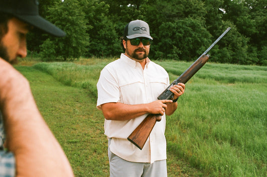 man shooting gun wearing Scout Shirt button down outdoors