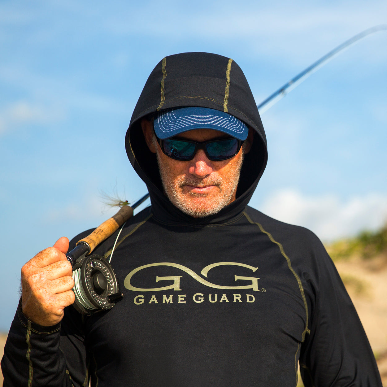 Man carrying a fishing pole wearing gameguard performance hoody