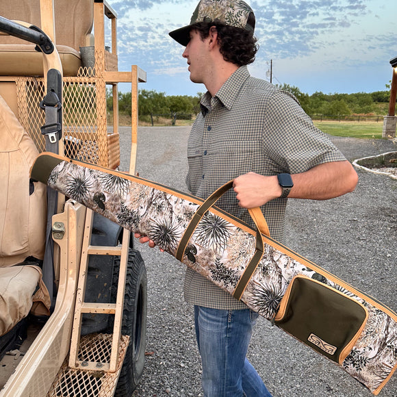 man carrying gameguard shotgun bag loading it into vehicle wearing tekcheck shirt and gameguard cap