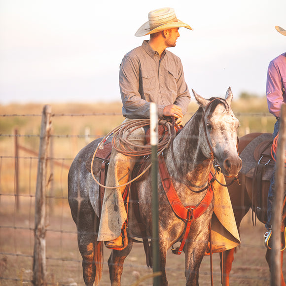 man riding horse wearing gameguard caviar pearl snap shirt and cowboy hat