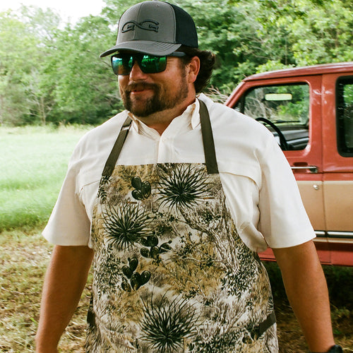 Man wearing GameGuard Apron outdoors getting ready to hop on the grill with friends